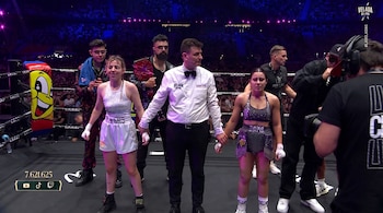 Dos boxeadoras, un árbitro, varias personas de sus equipos, un ring de boxeo y una multitud. Se muestra el número 7.621.625 y logos de plataformas.