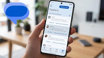 Una mano sostiene un smartphone mostrando la pantalla de la papelera de una app de mensajería, con listas de conversaciones eliminadas y opciones para restaurar/eliminar.