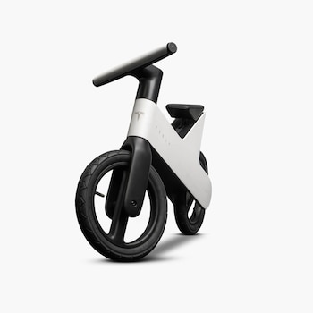 Bicicleta de equilibrio blanca y negra con el logotipo de Tesla en el cuadro, manillar plateado, sillín negro y dos ruedas