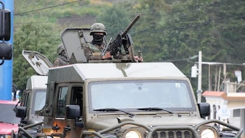 Fila de soldados en uniforme de camuflaje y boinas oscuras que sostienen sus armas