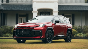 Interior de un Toyota RAV4 con volante multifunción negro y rojo, pantalla táctil central, panel de instrumentos digital y consola con palanca de cambios