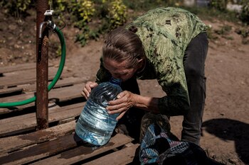 Una residente local bebe agua limpia de un bote que acaba de llenar, mientras continúa el ataque de Rusia contra Ucrania, en Sloviansk. REUTERS/Alkis Konstantinidis