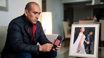 Un hombre calvo, Rafael Fernández, mira un teléfono con un mensaje sobre errores. Junto a él, una foto enmarcada de Karla Tarazona vestida de novia y su esposo.