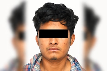 Retrato de un hombre con camisa a cuadros y los ojos cubiertos por una franja negra sobre fondo blanco con laterales desenfocados.