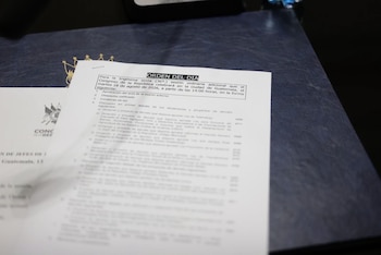 Una hoja de papel con el título "ORDEN DEL DIA" y texto sobre una sesión del Congreso de Guatemala. Una carpeta azul oscura con un logo dorado aparece debajo
