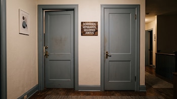 Dos puertas de madera azul en un pasillo junto a un cartel con el mensaje «Dormimos separados, seguimos juntos».