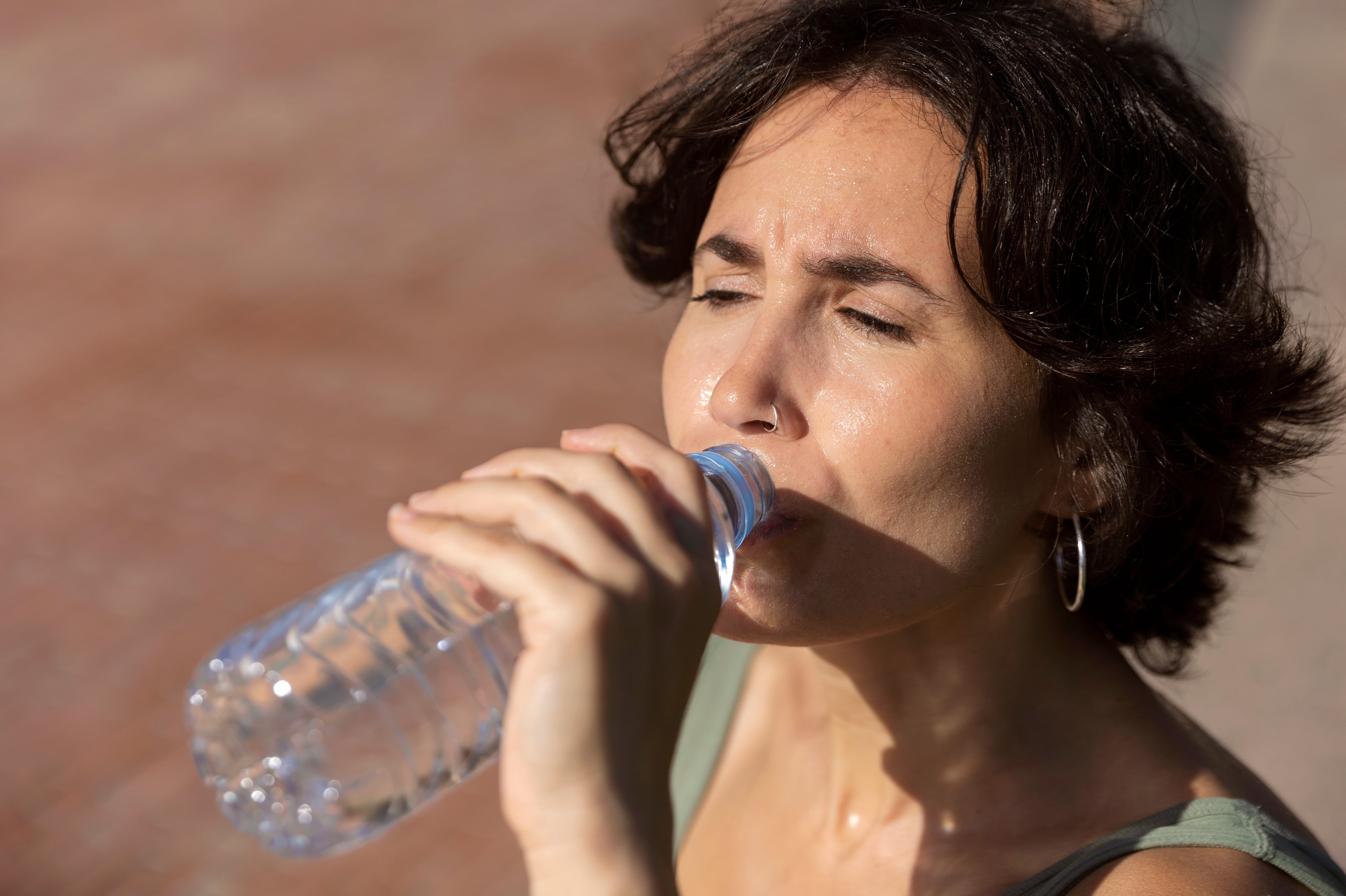 Una mujer bebiendo de una botella de agua (Magnific)