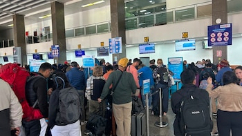 Una multitud de pasajeros con equipaje forma largas filas en los mostradores de facturación de un aeropuerto con carteles de JetSmart, Latam y CORPAC