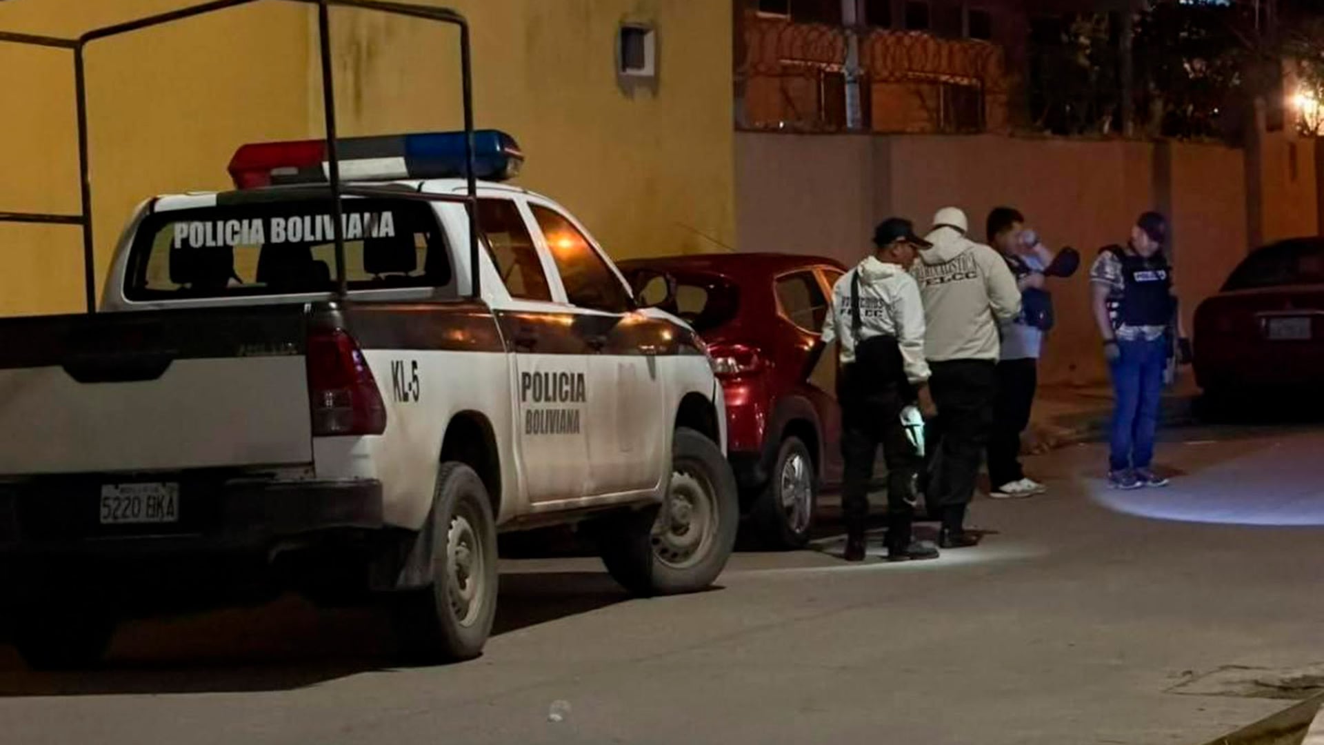 Agentes de la Policía Boliviana y vehículos policiales en el lugar donde fue asesinado el juez Víctor Hugo Claure en Bolivia.