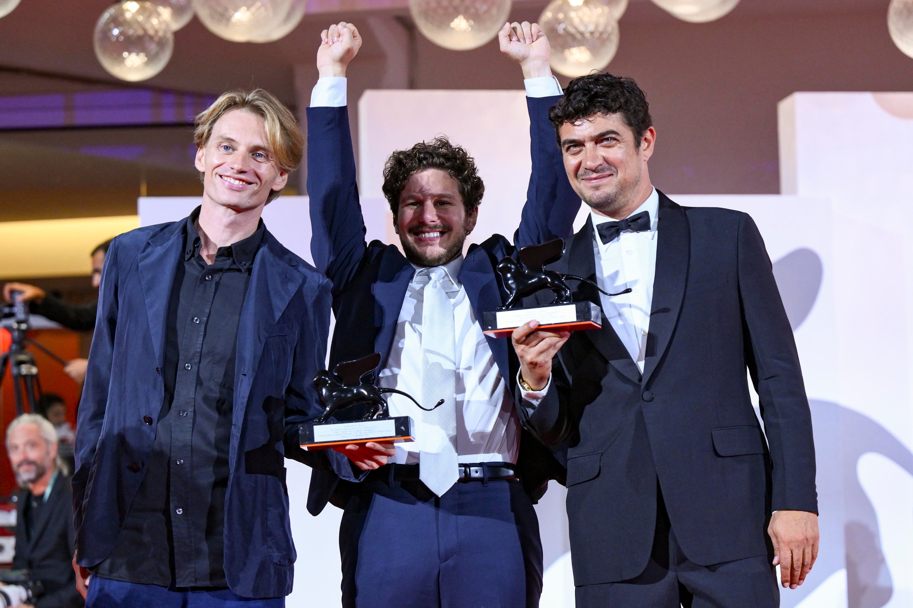 De izquierda a derecha, el guionista ítalo-alemán Damiano Femfert, el director italiano Tommaso Landucci y el actor italiano Riccardo Scamarcio sostienen los premios de la sección Horizontes por “I figli della scimmia”. (Ettore Ferrari/EFE)