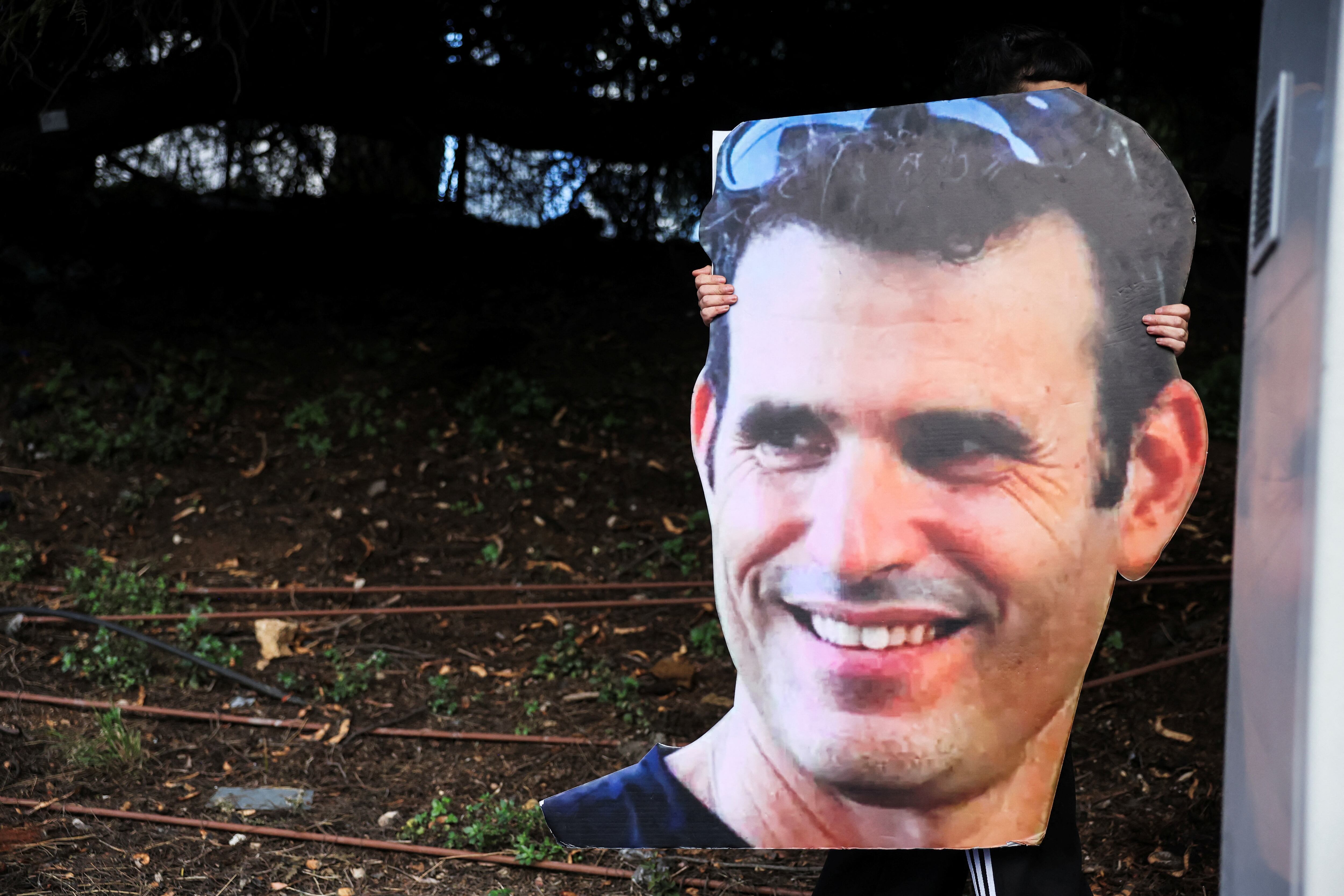 Una manifestante sostiene una foto recortada de la rehén israelí Dror Or mientras ella, junto con otros, bloquea una carretera durante una manifestación para exigir el regreso inmediato de los rehenes en febrero de 2025 (REUTERS/Nir Elias)