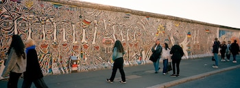 La gente se reúne en una pintura en East Side Gallery, en Berlín