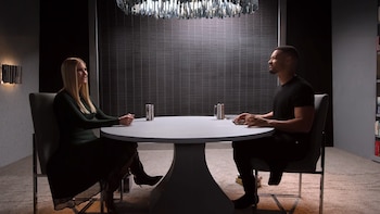 Ivanka Trump, com cabelos loiros lisos e vestido verde escuro, senta-se em frente a um homem em uma mesa redonda branca durante uma entrevista