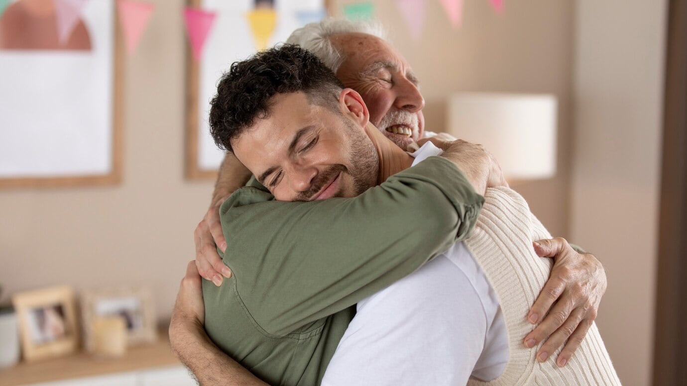 Adulto mayor dando un abrazo a su hijo (Freepik)