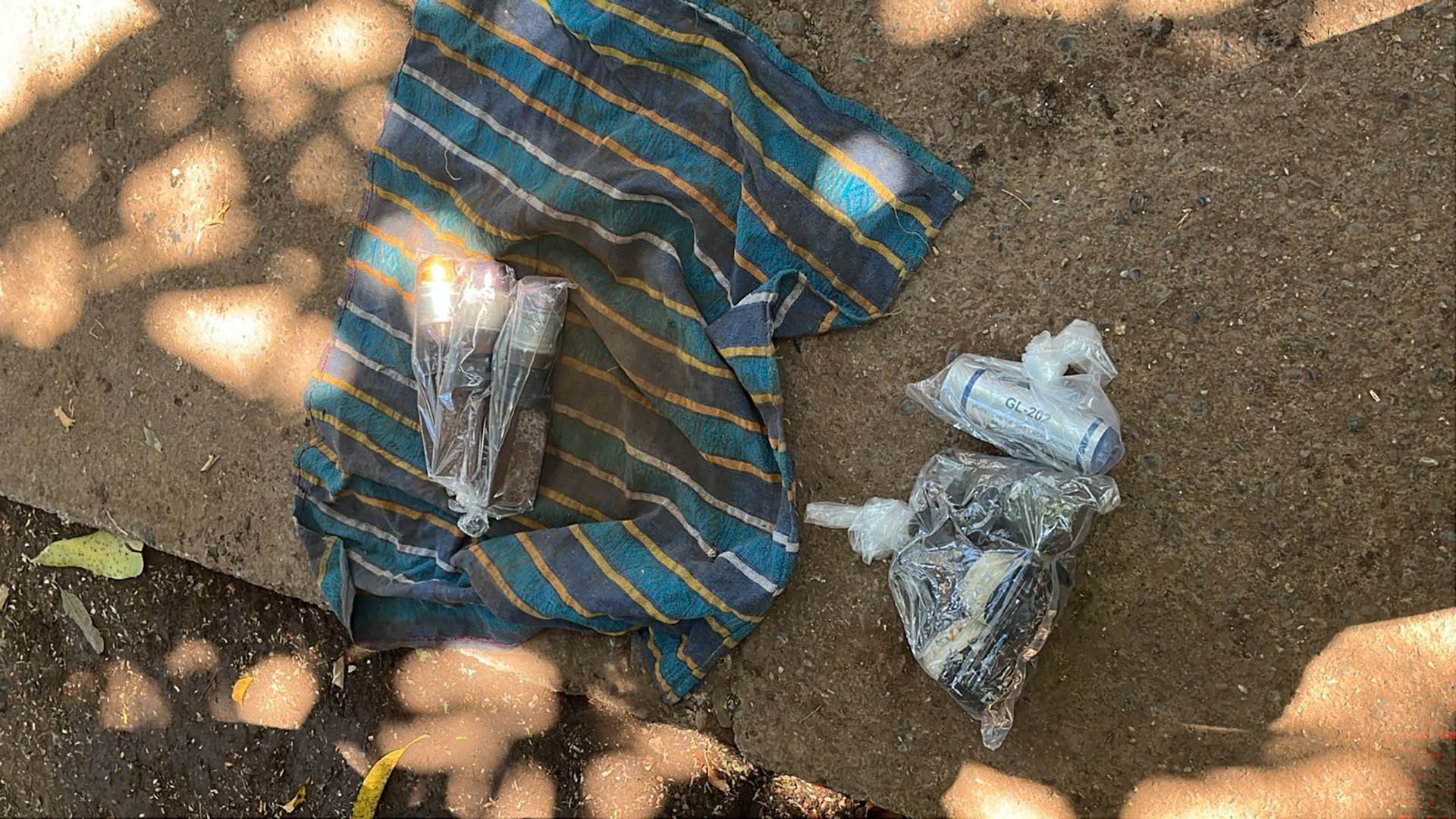 Elementos sospechosos, incluyendo un cilindro marcado GL-202 y otros paquetes plásticos, fueron incautados junto a una tela rayada, en lo que podría ser un sitio relacionado con WM. (Ministerio Público de Guatemala)