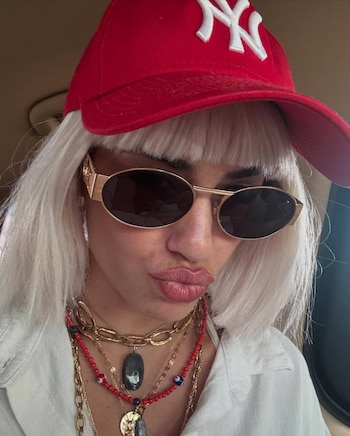 Con gorra, lentes y gesto