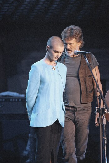 Kris Kristofferson consuela a Sinead O'Connor después de que la abuchearon fuera del escenario durante el concierto de aniversario de Bob Dylan en el Madison Square Garden de Nueva York, el 17 de octubre de 1992 (Foto AP/Ron Frehm, archivo)