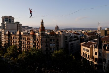 El funambulista francés Nathan Paulin recorre por un estrecho cable y en los dos sentidos los cerca de 350 metros que separan dos edificios entre la plaza Catalunya y el paseo de Gràcia, un espectáculo programado hoy domingo dentro del Grec Festival de Barcelona. EFE / Quique García.