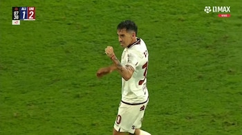Un jugador con camiseta blanca aprieta el puño en el césped mientras en la esquina superior figura un marcador digital de fútbol