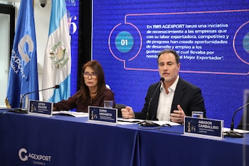 Once personas vestidas con trajes formales posan de pie delante de una pantalla azul con el logotipo del Galardón Nacional a la Exportación