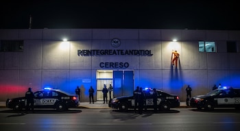 Edificio del Cereso con letrero "REINTEGRATEANTATIOL CERESO", tres patrullas con luces encendidas, varios agentes y un hombre de naranja desciende una pared.