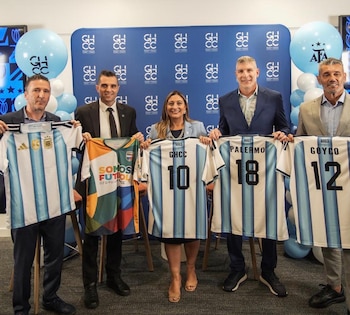 Cinco personas sostienen camisetas de fútbol. El fondo azul tiene logos GHCC y globos celestes y blancos con logos