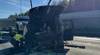 Vista de un accidente vehicular en una autopista con un SUV severamente dañado, un camión y un oficial de policía examinando los escombros