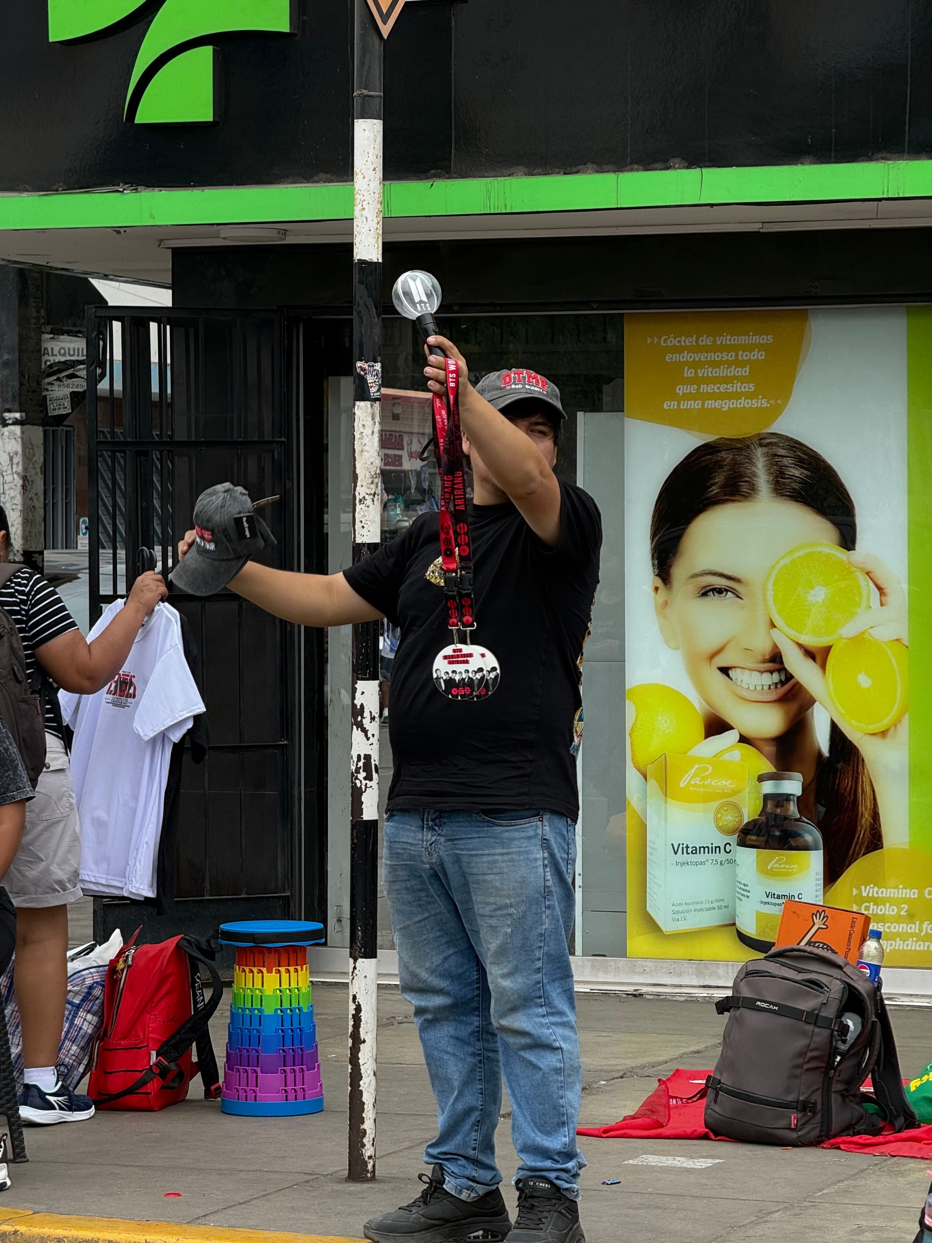 Un comerciante ambulante ofrece productos del grupo BTS en las inmediaciones del Estadio San Marcos en Lima. (Paula Díaz)