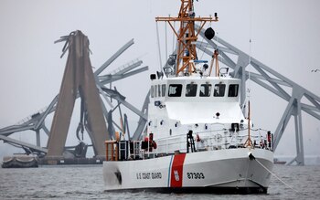 A U.S. Coast Guard vessel sails near the Francis Scott Key Bridge, after the Dali cargo vessel crashed into it causing it to collapse, in Baltimore, Maryland, U.S., March 27, 2024. REUTERS/Mike Segar