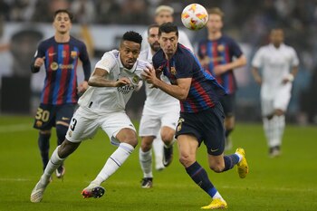 Eder Militao (izquierda) del Real Madrid y Robert Lewandowski del Barcelona pugnan por el balón en la final de la Supercopa española en Riad, Arabia Saudí, el domingo 16 de enero de 2023. (AP Foto/Hussein Malla)