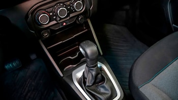 Interior de automóvil con palanca de cambios manual, consola central con controles de climatización, puerto USB, asiento de tela y pedal izquierdo