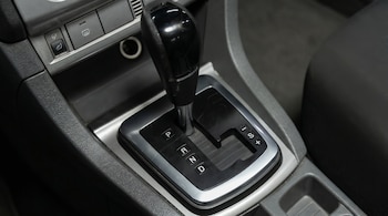 Primer plano de una palanca de cambios automática de color negro y gris en el interior de un coche, mostrando las letras P, R, N, D, S e I.