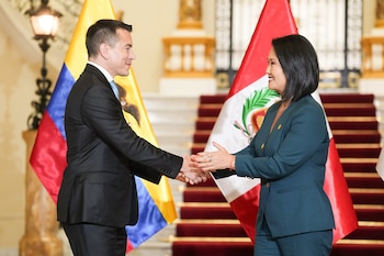 Daniel Noboa y Keiko Fujimori se dan la mano en un salón con escaleras alfombradas, frente a las banderas de Ecuador y Perú