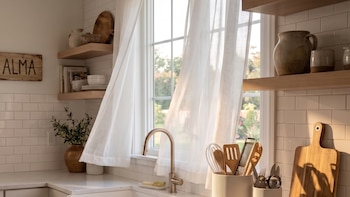 Una cocina con azulejos blancos, un fregadero, utensilios y un cartel de madera con el texto Lavabo y Alma junto a la ventana.
