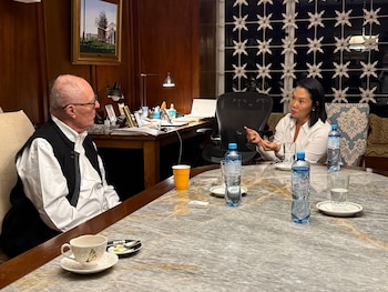 Keiko Fujimori y Pedro Pablo Kuczynski sentados frente a frente en una mesa de mármol; Fujimori gesticula, Kuczynski escucha. Hay botellas de agua y vasos