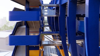 Vista detallada de un edificio moderno con múltiples niveles, escaleras y pasarelas en tonos azules y amarillos, y estructuras metálicas