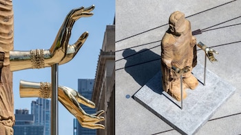 Escultura en The High Line Plinth con una figura de tronco tallado y dos manos doradas que emergen, apoyadas en postes de metal sobre una base de granito