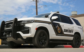 Vehículo utilitario deportivo de color blanco con la inscripción Bexar County SHERIFF en un lateral, estacionado al aire libre