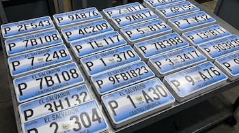 Múltiples placas vehiculares de El Salvador apiladas, azules y blancas. Muestran números, letras, el escudo nacional y el año 2011.