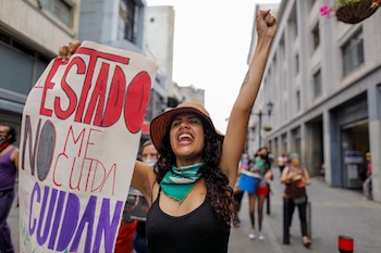 A woman rises her hand during a protest of the Tinta Violeta feminist collective to mark International Women's Day, in Caracas, Venezuela March 8, 2021. The banner reads: "The State doesn't take care of me." REUTERS/Leonardo Fernandez Viloria NO RESALES. NO ARCHIVES