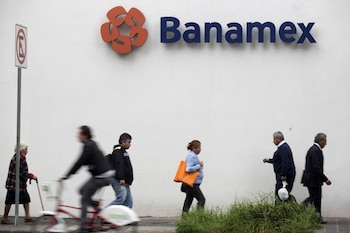 Pedestrians walk underneath a Banamex