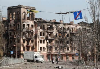 Residentes locales caminan por una calle junto a un edificio destruido por las tropas rusas en la ciudad portuaria del sur de Mariupol (REUTERS/Alexander Ermochenko)
