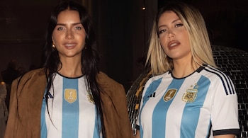 Dos mujeres con cabello oscuro y rubio visten camisetas de fútbol celestes y blancas con el escudo de Argentina y el logo de la FIFA.