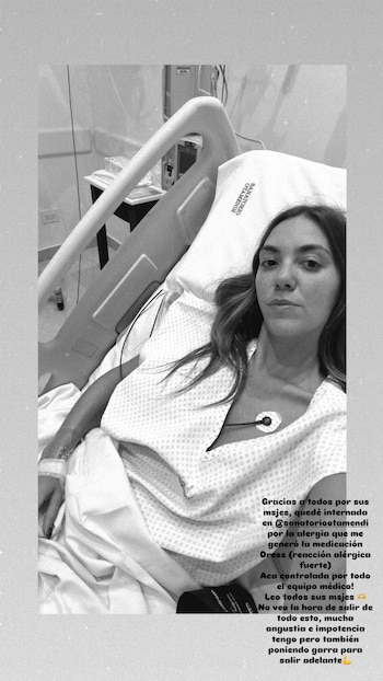 Floppy Tesouro recostada en una cama de hospital con bata blanca, catéter intravenoso en el brazo izquierdo y un electrodo en el pecho. El logo "Sanatorio Otamendi" se ve en la almohada