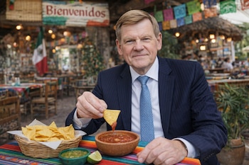 Un hombre de traje, Johann Wadephul, come un totopo con salsa en un restaurante mexicano. Hay una canasta de totopos, dos salsas y una lima sobre la mesa colorida.