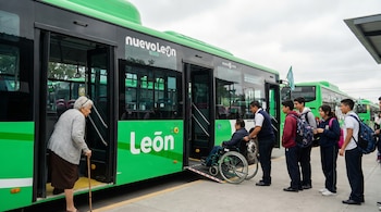 Una persona adulta mayor con bastón, una persona en silla de ruedas con asistencia y jóvenes estudiantes suben a un autobús verde de "Nuevo León" y "León".