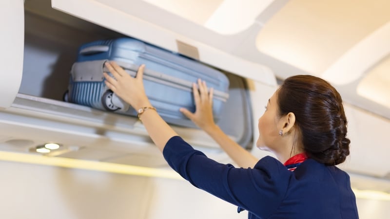 Azafata colocando una maleta en un avión. (Shutterstock)