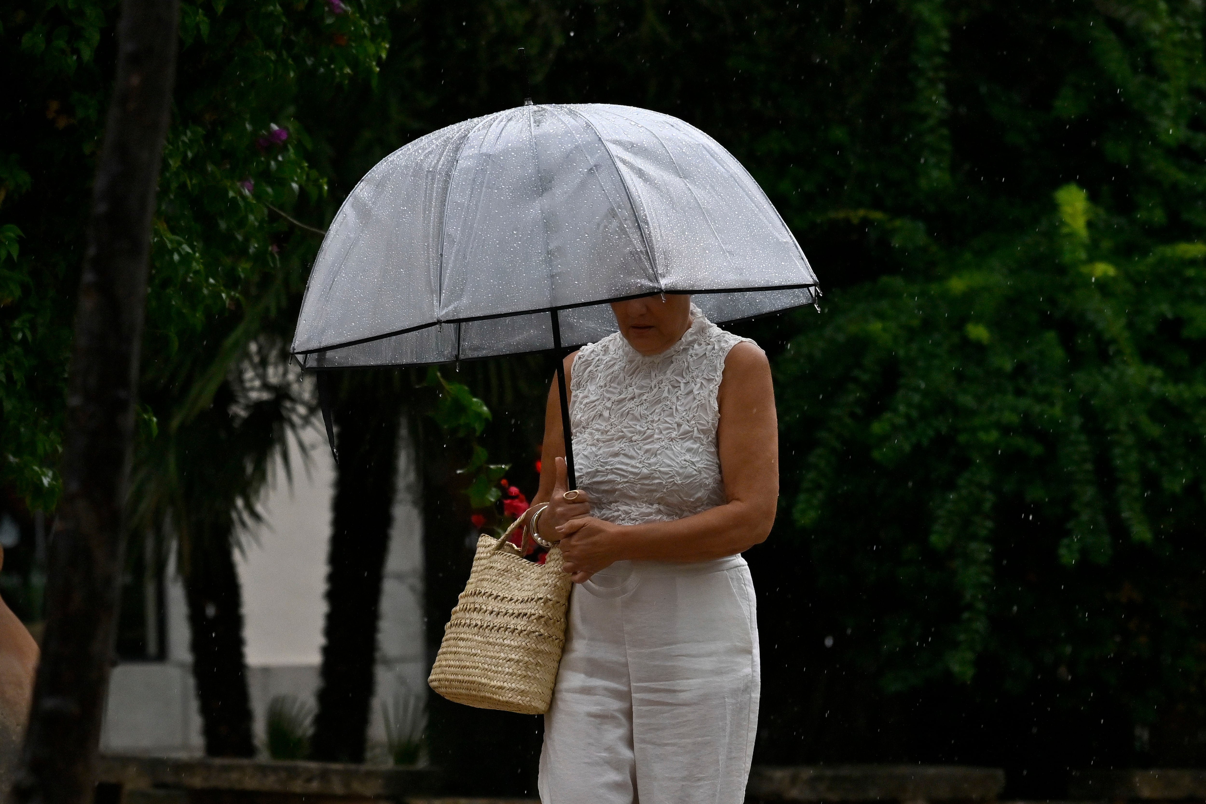 Una mujer se protege de la lluvia caída este miércoles en Palma. (Miquel A. Borràs/EFE)