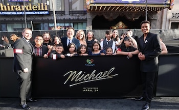 Varias personas posan detrás de una barrera negra con el título de la película Michael y el logo de Heal Los Angeles Foundation