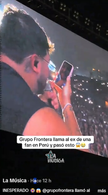 Pantalla de concierto que proyecta a un cantante mientras sostiene un teléfono móvil frente al público durante una presentación nocturna